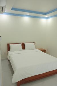 a bed with white sheets and pillows in a room at Ti Do Homestay in Ðức Hòa