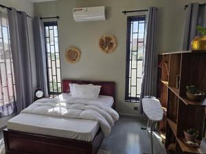 a bedroom with a bed and a chair and windows at Verified Stone House in Dodoma
