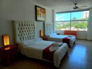a hotel room with two beds and a window at VILLA COSTERA HOTEL BOUTIQUE in Acapulco