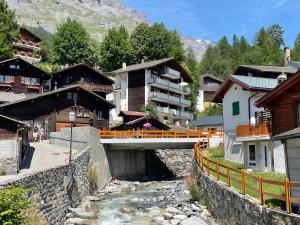 a bridge over a river in a village with buildings at Apartments Soldanella in Leukerbad