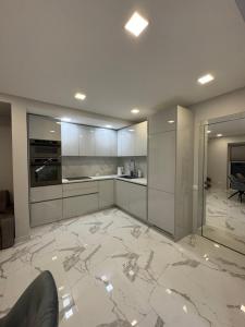 a kitchen with white cabinets and a marble floor at Kaleju 10 Apartment in Tukums