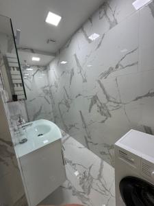 a bathroom with a white sink and a marble wall at Kaleju 10 Apartment in Tukums +22 photos