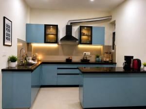 a large kitchen with blue cabinets and a sink at Halfway Home Cozy 2bhk in Rājpur