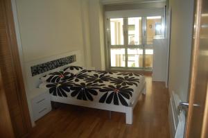 a bedroom with a bed with a black and white comforter at Apartamentos Cedeira in Cedeira