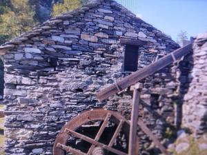 an old stone building with a window and a wheel at casa della marsiglia in Curiglia