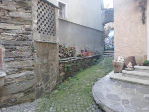 an alley with a stone wall and some potted plants at casa della marsiglia in Curiglia