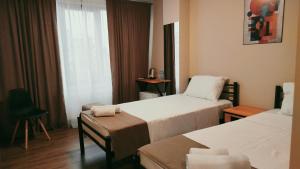 a hotel room with two beds and a chair at Hotel Aura in Zugdidi