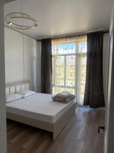 a bedroom with a bed and a large window at Береке гостевой дом in Bosteri