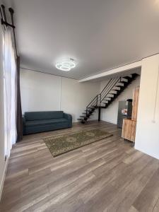 a living room with a couch and a staircase at Береке гостевой дом in Bosteri