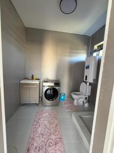 a small bathroom with a washing machine and a toilet at Береке гостевой дом in Bosteri