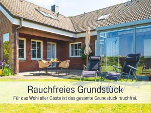 a house with chairs and an umbrella on a patio at Huus Binnensee - Erdgeschoss-Wohnung mit Garten & Seeblick - Wintergarten & Terrasse - hundefreundlich - ruhige Lage - Südstrand 5 Min mit Rad in Fehmarn +56 photos