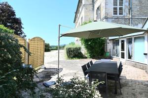 a patio with a table and an umbrella at L'Ecrin du Chalet d'Arguel in Pugey