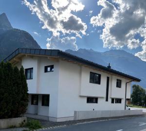a white building with mountains in the background at 6444 Apartment in Unterlängenfeld