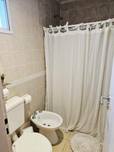 a bathroom with a toilet and a white shower curtain at departamento Malbec cosecha 17 in Ciudad Lujan de Cuyo