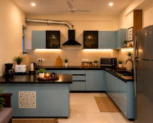 a kitchen with blue cabinets and a refrigerator at The Azure Loft Nestory Stays in Rājpur