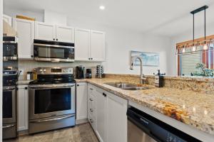 a kitchen with stainless steel appliances and white cabinets at Hauts-bois Ski Inout 2brs Wpool Access 193-1 in Mont-Tremblant +27 photos