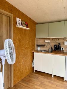 a kitchen with white cabinets and a white fan at Sajūtu dārza mājiņa in Augšlīgatne