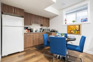 a kitchen with a white refrigerator and a table with blue chairs at Plush Suite Pet Friendly 326 Mbps Wi-Fi in Airdrie