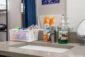 a bathroom counter with a sink with hygiene products on it at Plush Suite Pet Friendly 326 Mbps Wi-Fi in Airdrie +19 photos