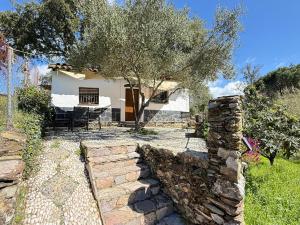 a house with a tree and a stone wall at Casa Papiqui in Fuenteheridos +46 photos