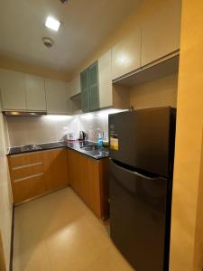 a kitchen with a black refrigerator and wooden cabinets at 8 Newtown Mactan in Pajo