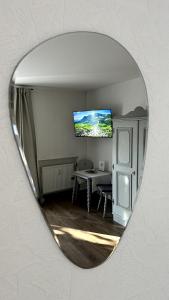 a mirror reflecting a room with a table and a tv at Gästehaus Zoller - Rettenberg im Allgäu in Rettenberg