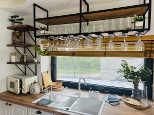 a kitchen with a sink and glasses on a shelf at Siedlisko in Tuchów