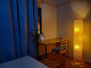 a bedroom with a desk with a fan and a chair at Au cœur de Ouidah in Ouidah