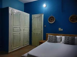 a bedroom with blue walls and a bed and a door at Au cœur de Ouidah in Ouidah