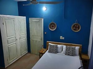 a blue bedroom with a bed and a blue wall at Au cœur de Ouidah in Ouidah
