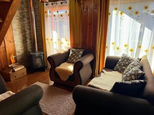a living room with two chairs and a couch and a window at Refugio Barbara Coñaripe in Coñaripe