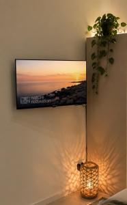 a tv on a wall with a picture of a sunset at La maison du hérisson in Flines-lès-Mortagne