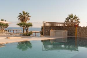a swimming pool in front of a building with palm trees at PHEIA, Vriniotis Resorts in Katakolo