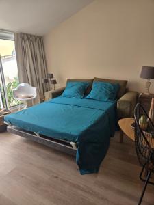 a bedroom with a bed with blue sheets and a couch at Chez mamie in La Rochelle