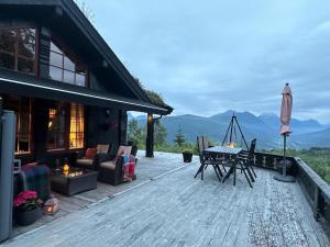 a house with a deck with a table and chairs at The View - Mountain cabin with stunning views in Stranda