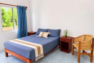 a bedroom with a bed and a chair and a window at Punta Sol in Brisas de Zicatela