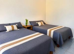 two beds in a room with blue and white sheets at Punta Sol in Brisas de Zicatela