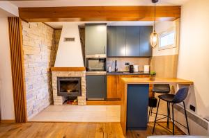 a kitchen with a fireplace and a counter with chairs at Wolf Apartments Zabljak in Žabljak