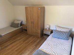 ein Schlafzimmer mit zwei Betten und einem Holzschrank in der Unterkunft Sobe HUBERTUS Lipovac Bajakovo in Lipovac