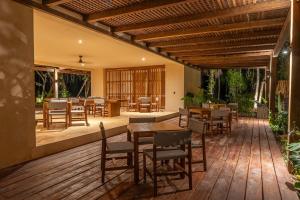 a patio with tables and chairs on a wooden deck at PenthouseLuxury - Laguna PoolPriv Paddles in Bacalar