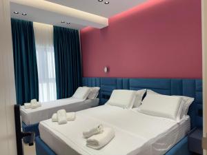 two beds in a room with a red wall at Hotel Kloi - Rooms & Jacuzzi Vlore in Vlorë