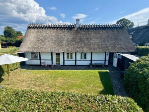 a small white house with a thatched roof at Fred & Lyst in Stenløse