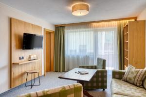 a hotel room with a couch and a table and a tv at Naturhotel Falknerhof in Niederthai