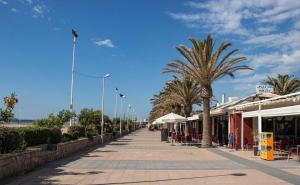 a street with palm trees and tables and buildings at Duna Hollidays in Puerto de Sagunto