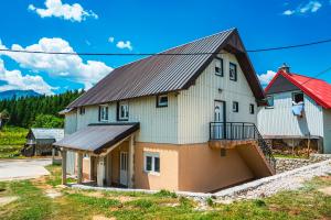 a large white house with a black roof at Wolf Apartments Zabljak in Žabljak