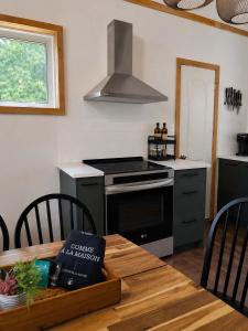 a kitchen with a stove and a table with a book at Le Lac Apaisant - Rustic Haven by the Water in Saint-Calixte