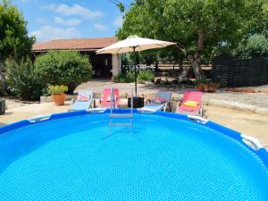 a swimming pool with chairs and an umbrella at Refúgio das Artes Guesthouse in Porto de Mós