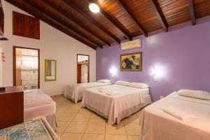 three beds in a room with purple walls at Pousada das Orquídeas in Pirenópolis +49 photos
