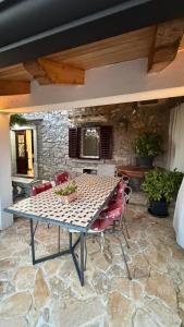 a patio with a table and chairs and a stone wall at House Pelcic Kostrena in Kostrena