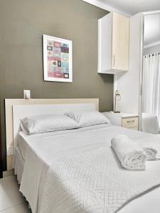a bedroom with a large bed with white sheets at Quarto 2P Joinville Costa e Silva perto Centro in Joinville